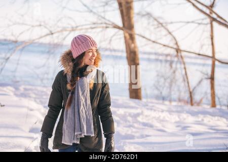 Femme d'hiver marchant sur la forêt promenade dans la nature froide en plein air rivière à l'extérieur. Happy asian girl modèle portant un chapeau en laine, un foulard et une veste de fourrure Banque D'Images