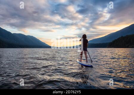 Femme paddleboard sur le lac Scenic au coucher du soleil Banque D'Images