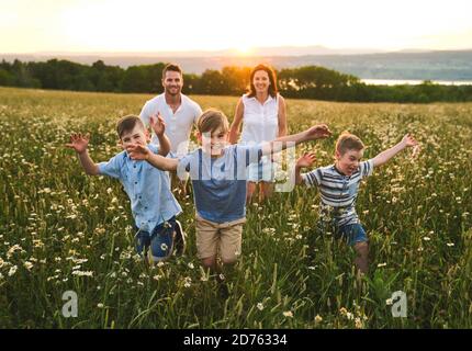 Bonne famille sur le champ de pâquerettes au coucher du soleil temps ensemble courir ensemble Banque D'Images