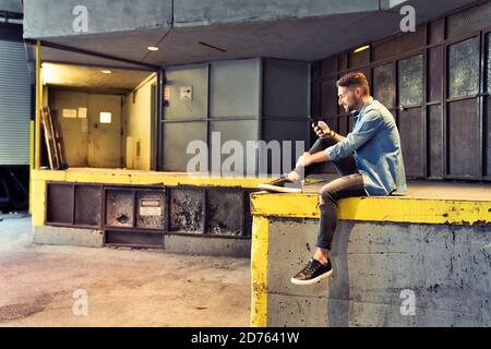 homme sur le fond de sous-sol dans la ville en utilisant le téléphone cellulaire Banque D'Images