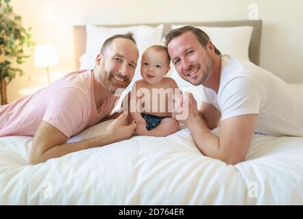 Parents homosexuels de sexe masculin se détendant au lit avec bébé Banque D'Images