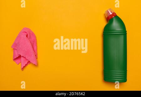 chiffon pour le nettoyage et bouteille verte avec liquide pour le nettoyage des toilettes sur fond jaune. place pour le texte. Banque D'Images