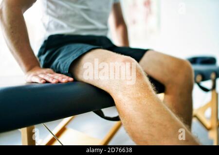 Un lieu moderne de physiothérapie de réadaptation avec l'homme client s'asseoir sur tableau Banque D'Images