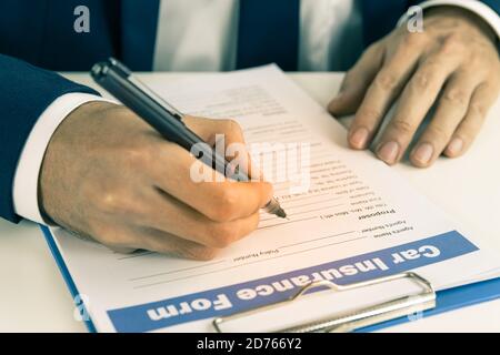 L'agent d'assurance Zoom écrit à la main le formulaire de demande de remboursement d'assurance automobile ou Document d'assurance sur la vue latérale de la table de bureau en version vintage Tonalité Banque D'Images