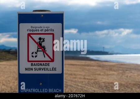 Panneau d'avertissement écrit en français indiquant « plage non patrouillée » sur la côte atlantique. « le bain à vos risques » écrit en français au sommet Banque D'Images