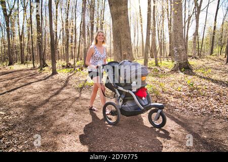 Une jeune mère en train de courir tout en poussant une poussette dans le stationnement Banque D'Images