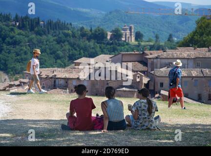 trois filles assises sur une pelouse à l'ombre de Un arbre mange des sandwiches et observe la ville d'Urbino par le haut Banque D'Images