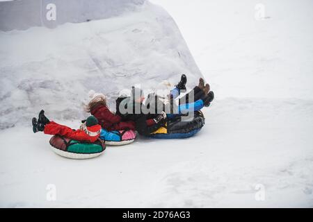 La mère, le père, le fils et la fille passent l'hiver d'un toboggan de glace sur un tubing multicolore. Banque D'Images