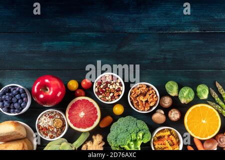 Variété de produits alimentaires végétaliens, prise de vue en hauteur avec espace de copie. Fruits et légumes, légumineuses, champignons, noix, un plat sur fond sombre Banque D'Images