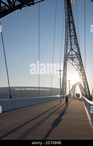 Jogger sur le pont Matagarup, traversant la rivière Swan, au lever du soleil. Banque D'Images