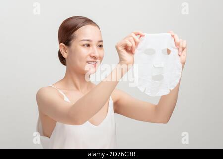 Jeune femme dans une serviette attachée sur sa tête appliquant masque hydratant pour le visage Banque D'Images