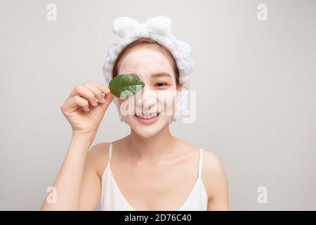 une fille souriante avec une serviette blanche sur sa tête appliqué un masque hydratant en argile Banque D'Images