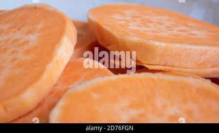 Tranchez les patates douces l'une sur l'autre dans une casserole en céramique. L'agrafe orange vif est un substitut sain pour la pomme de terre ou les frites. Banque D'Images