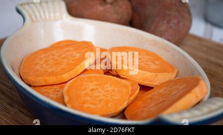 Tranchez les patates douces l'une sur l'autre dans une casserole en céramique. L'agrafe orange vif est un substitut sain pour la pomme de terre ou les frites. Banque D'Images