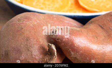 Deux patates douces en vedette, placées sur une planche de bois. L'agrafe orange vif est un substitut sain pour la pomme de terre ou les frites. Banque D'Images