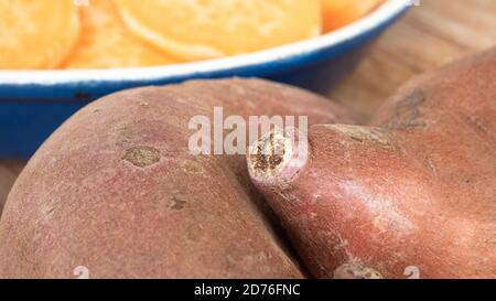 Deux patates douces en vedette, placées sur une planche de bois. L'agrafe orange vif est un substitut sain pour la pomme de terre ou les frites. Banque D'Images