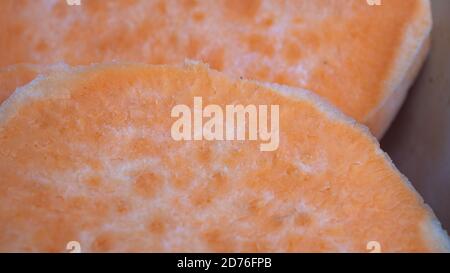 Tranchez les patates douces l'une sur l'autre dans une casserole en céramique. L'agrafe orange vif est un substitut sain pour la pomme de terre ou les frites. Banque D'Images