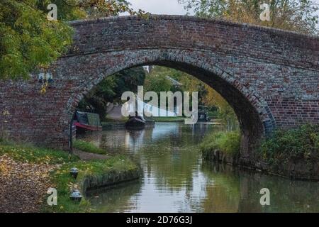 pont au-dessus du canal de la grande union avec des bateaux étroits et des barges amarrés le long du chemin de halage à braunston, daventry, royaume-uni Banque D'Images