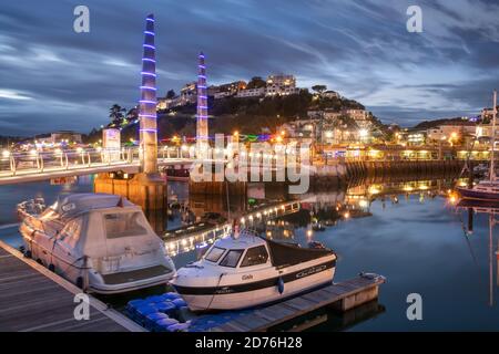 Après une journée de soleil et de douches sur la côte sud, tandis que le soleil se couche, les lumières s'allument autour de la marina et du Harbour Bridge à Torquay sur le 'The Eng Banque D'Images