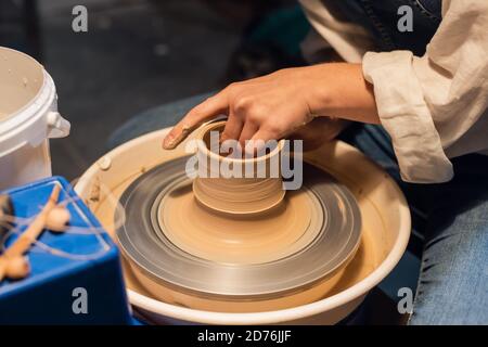 maître de classe sur la sculpture d'un pot dans un atelier d'art. la fille derrière la roue de potier fait un blanc avec ses mains Banque D'Images