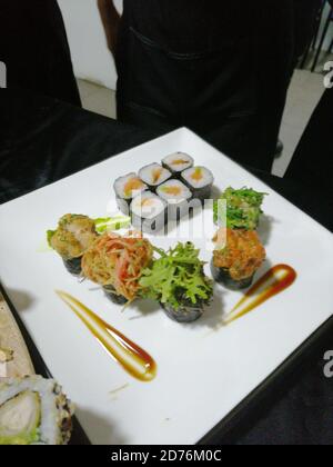 Plan vertical de différents rouleaux de sushi plaqués sur un blanc plaque avec une belle présentation Banque D'Images