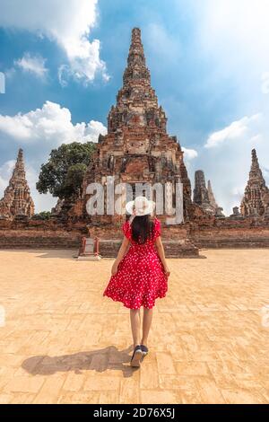 Femme touristique asiatique en robe rouge et chapeau de soleil de la vue arrière, en marchant à travers le beau château historique et le temple historique à Ayutthaya, Thaïlande Banque D'Images