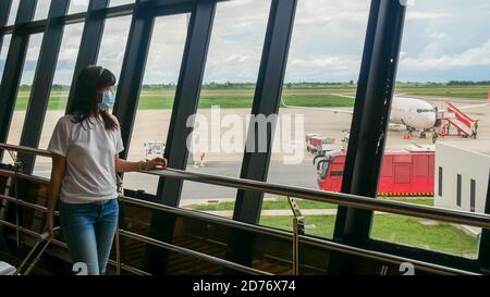 Touriste asiatique avec des bagages à roulettes, portant un masque hygiénique pour prévenir la pandémie pendant le voyage au terminal de l'aéroport. Nouveau normal après le coronavirus covid-19 Banque D'Images