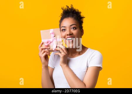 Femme afro-américaine secouant le cadeau de Noël au Studio Banque D'Images