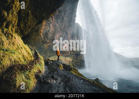 Homme aventureux debout sous la cascade, la chute d'eau Seljalandsfoss dans la partie sud de l'Islande Banque D'Images