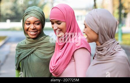 Trois femmes musulmanes gaies dans hijab marcher et parler à l'extérieur Banque D'Images