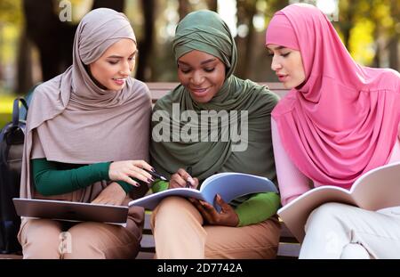 Trois étudiantes arabes apprendre ensemble à lire des livres assis à l'extérieur Banque D'Images