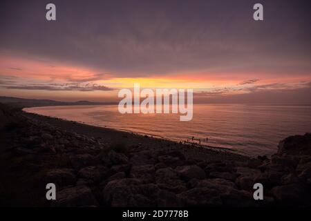 Coucher de soleil Golden hour à Colwyn Bay, au nord du pays de Galles. Ciel chaud et vagues douces le long d'une côte rocheuse Banque D'Images