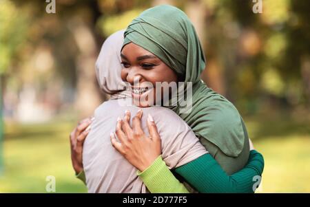 Deux femmes musulmanes heureuses dans le foulard hijab embrassant Meeting Outdoors Banque D'Images