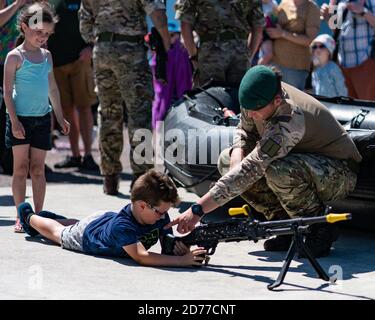 Royal Marine Commando donne des conseils sur l'utilisation d'une mitrailleuse À un jeune garçon à leur exposition au Llandudno Journée des forces armées Banque D'Images