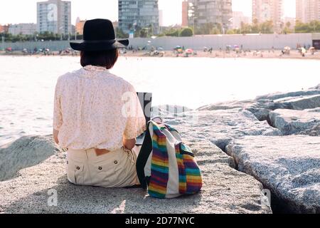 vue arrière d'une jeune femme voyageur travaillant avec un ordinateur portable et un sac à dos près de la mer à côté de la ville, concept de nomade numérique et de style de vie de blogueur , cop Banque D'Images