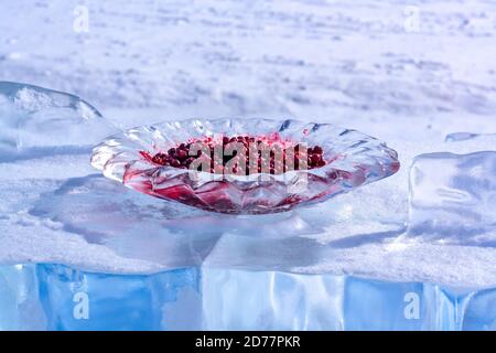 Les canneberges rouges dans une plaque de glace se trouvent sur un morceau de glace. La glace est arrosée de neige. Tradition russe sibérienne de rencontrer des invités. Se concentrer sur un p Banque D'Images