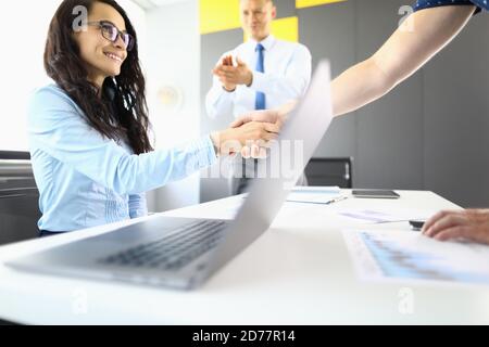 Femme d'affaires et partenaires au bureau se secouent les mains et se maloque Banque D'Images