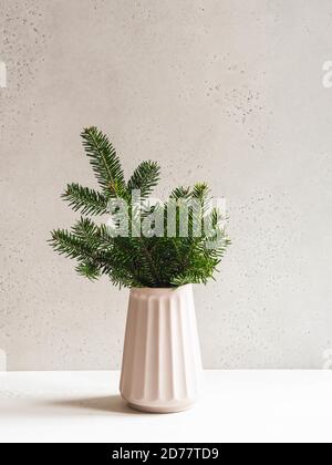 Composition de noël minimaliste avec branches de sapin dans un vase en céramique moderne sur fond gris. Vue avant. Copier l'espace Banque D'Images