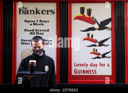 Enzo Gach, barman au pub Bankers dans le centre-ville de Dublin, se prépare à servir un client avec une pinte de Guinness comme restaurants, Les cafés et les bars ne peuvent fournir des services de plats à emporter qu'à partir de minuit ce soir, car toute l'Irlande sera soumise à des restrictions de niveau 5 pour six semaines afin de lutter contre l'augmentation des cas de virus. Banque D'Images