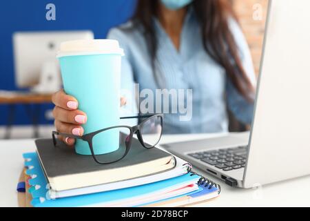 La main féminine tient une tasse de café sur le lieu de travail. Banque D'Images