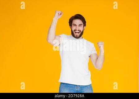 Portrait d'un homme barbu joyeux célébrant le succès isolé arrière-plan jaune Banque D'Images