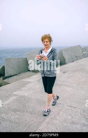 Senior sportswoman marchant et regardant son smartphone Banque D'Images
