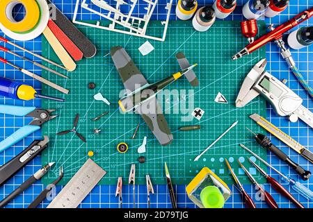 vue sur le bureau depuis le dessus de l'assemblage et la peinture de l'arrière-plan du concept d'avion de chasse modèle rétro. outils de modélisation aérographe pistolet pièces de kit de peinture bl Banque D'Images