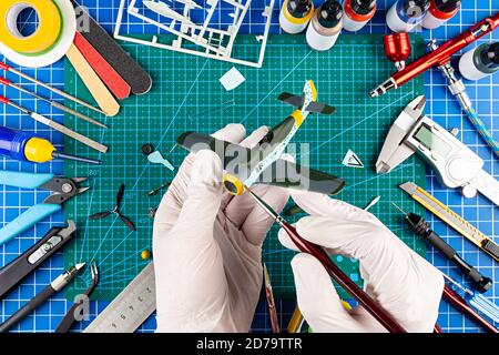 vue sur le bureau depuis le dessus de l'assemblage et la peinture de l'arrière-plan du concept d'avion de chasse modèle rétro. outils de modélisation aérographe pistolet pièces de kit de peinture bl Banque D'Images