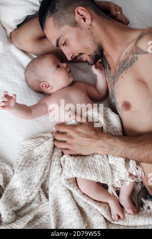 homme avec bébé. famille heureuse à la maison. père heureux avec mignon bébé garçon de deux mois allongé dans un lit léger à la maison Banque D'Images