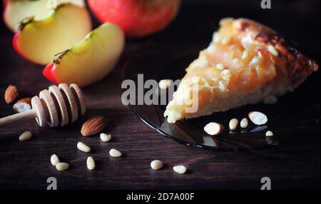 Charlotte avec pommes et noix. Préparation de la cuisson de pommes avec des noix et du miel. Dessert des produits cuits à partir de pommes et de noix avec du miel sur une table en bois. Banque D'Images