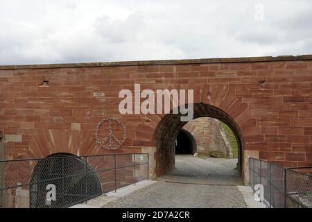 Un symbole de paix fait de barbelés et de petites figures en forme de corps humains attachés sur un mur forteresse ou citadelle à Belfort, France. Banque D'Images