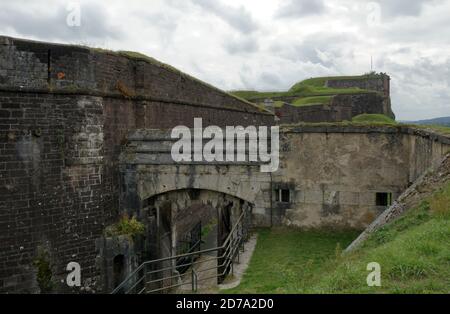 Forteresse ou citadelle à Belfort, France. La porte d'entrée et les murs extérieurs sont constitués de blocs de pierre partiellement couverts d'herbe ou de pelouse bien entretenue. Banque D'Images