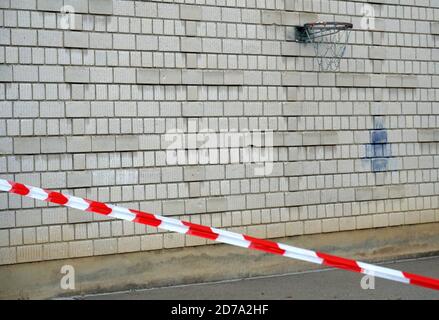 Panier de basket fixé sur un mur de briques. Au premier plan, il y a un ruban barrière de blanc rouge comme mesure préventive dans la deuxième vague de corona Banque D'Images