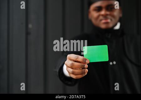 L'homme africain porte du durag noir tient le drapeau de la Libye à la main isolé arrière-plan sombre. Banque D'Images